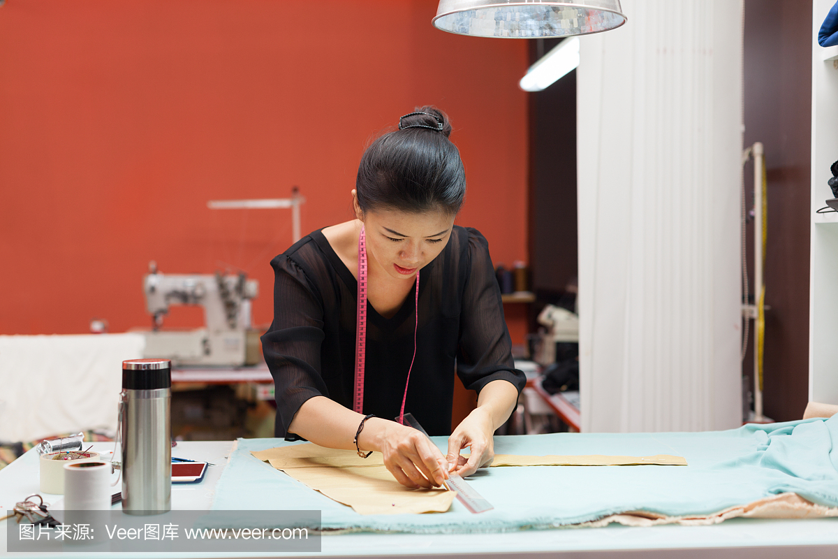 亚洲女人裁缝时装服装设计师与织物的工作